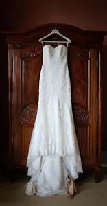 wedding photography Orchardleigh House Photos show a wedding dress gracefully hanging on a dresser in a room.