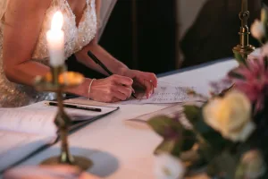 A bride signing her wedding vows at Orchardleigh House, surrounded by candles.