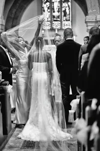 Orchardleigh Wedding Photography captures the beautiful moment of a bride walking down the aisle with her veil.