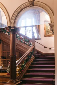 An ornate staircase in Orchardleigh House adorned with Christmas decorations.