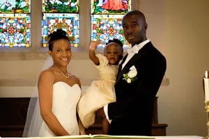 wedding photography Orchardleigh Wedding Photography captures an enchanting moment of a bride and groom standing gracefully in front of a breathtaking stained glass window.