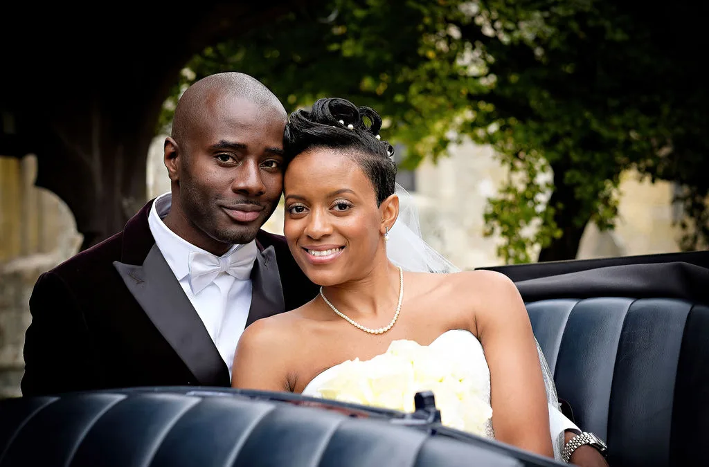 A newlywed couple posing in a black car captured by their wedding photographer in Bath.