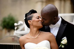 wedding photography Orchardleigh Wedding Photography captures a beautiful moment of a bride and groom kissing in front of a car.