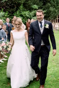 A bride and groom gracefully walking down the aisle of The Manor Castle Combe, with confetti joyfully thrown at them. Captured beautifully by a talented Wedding Photographer.