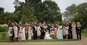 Orchardleigh Wedding Photography captures a picturesque moment as a wedding party beautifully poses for a photo amidst the lush greenery of a garden.