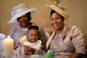 wedding photography Three women in hats, captured during an Orchardleigh Wedding Photography shoot, sitting at a table with a baby.