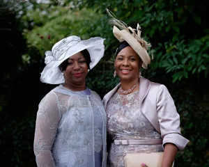 Two women in elegant dresses and chic hats striking a pose for a photo.
Keywords: Photographer Dress