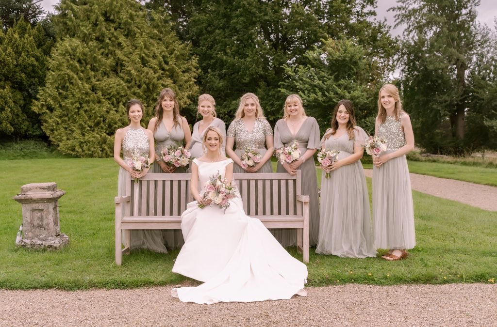 a bride and her bridesmaids sitting on a bench.