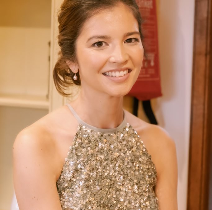 a woman in a sparky dress smiling at the camera.