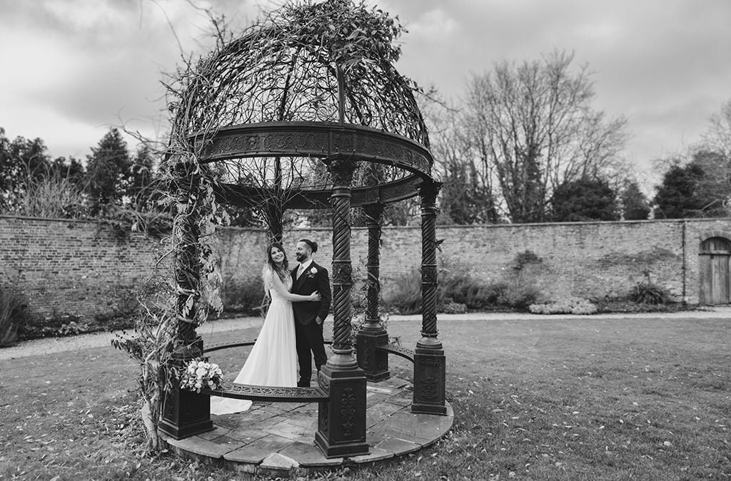 A black and white photo of a bride and groom in front of a gazebo captured by Wedding Photographer Orchardleigh.