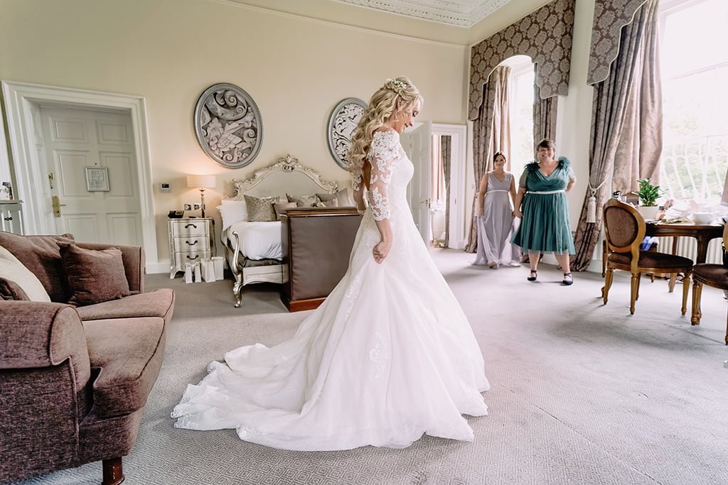 a woman in a wedding dress standing in a living room.