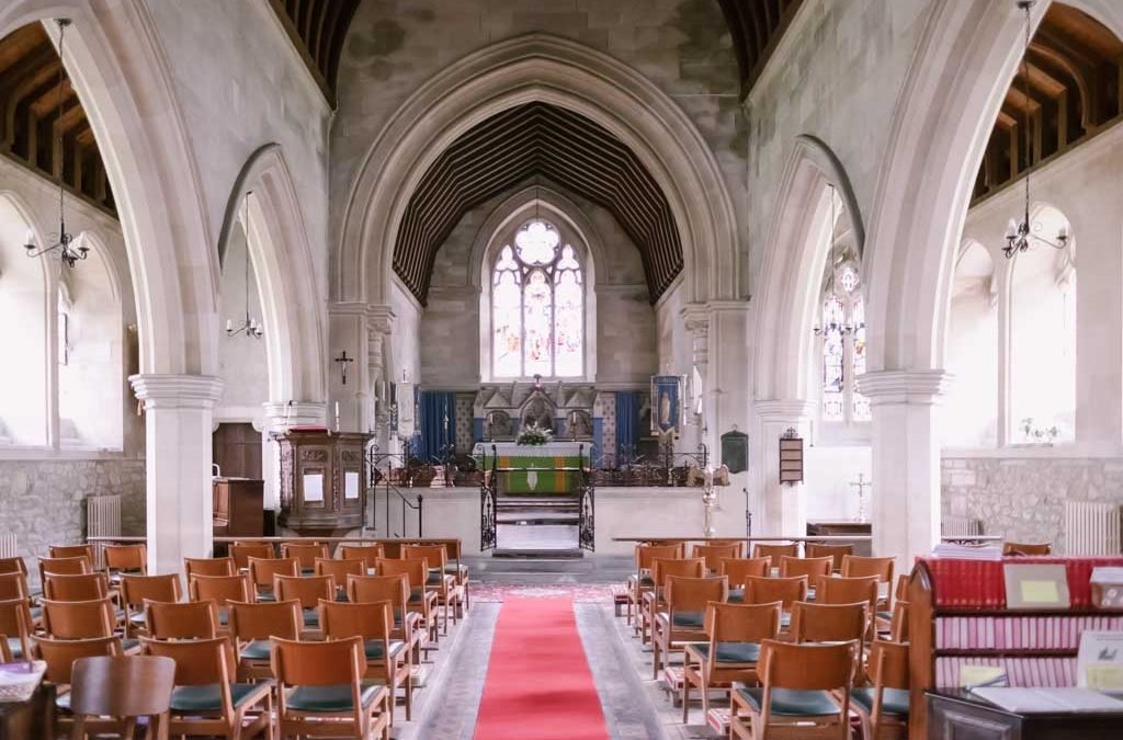 a church filled with wooden chairs and a red carpet.