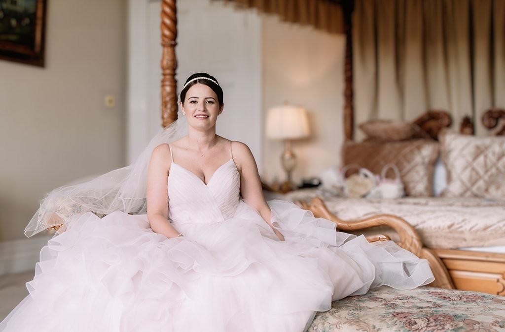 a woman in a wedding dress sitting on a bed.