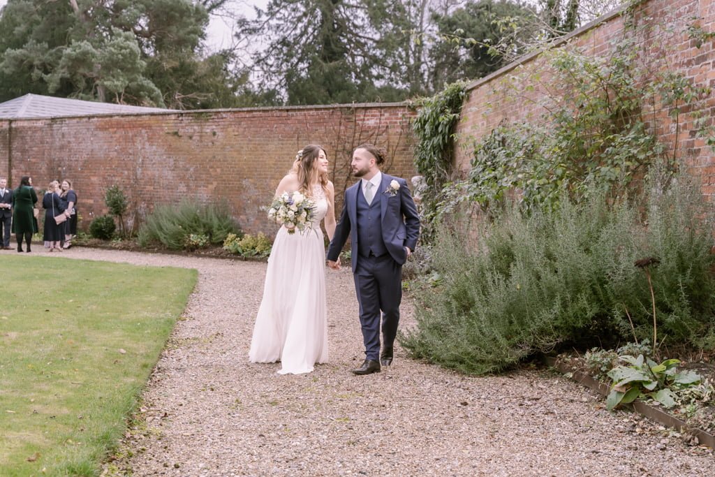 a bride and groom walking through a garden.