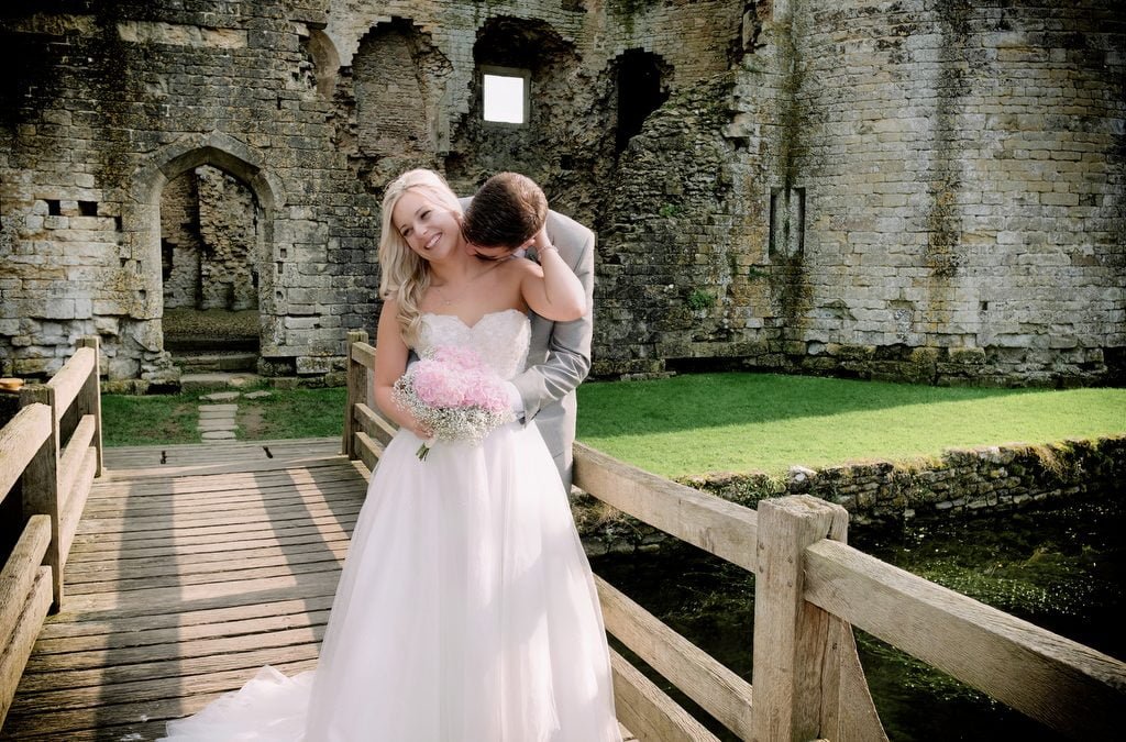 a bride and groom kissing on a bridge.