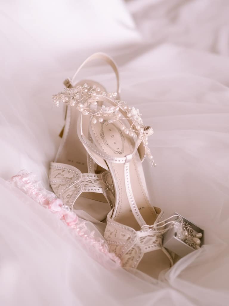 a pair of wedding shoes on a bed.