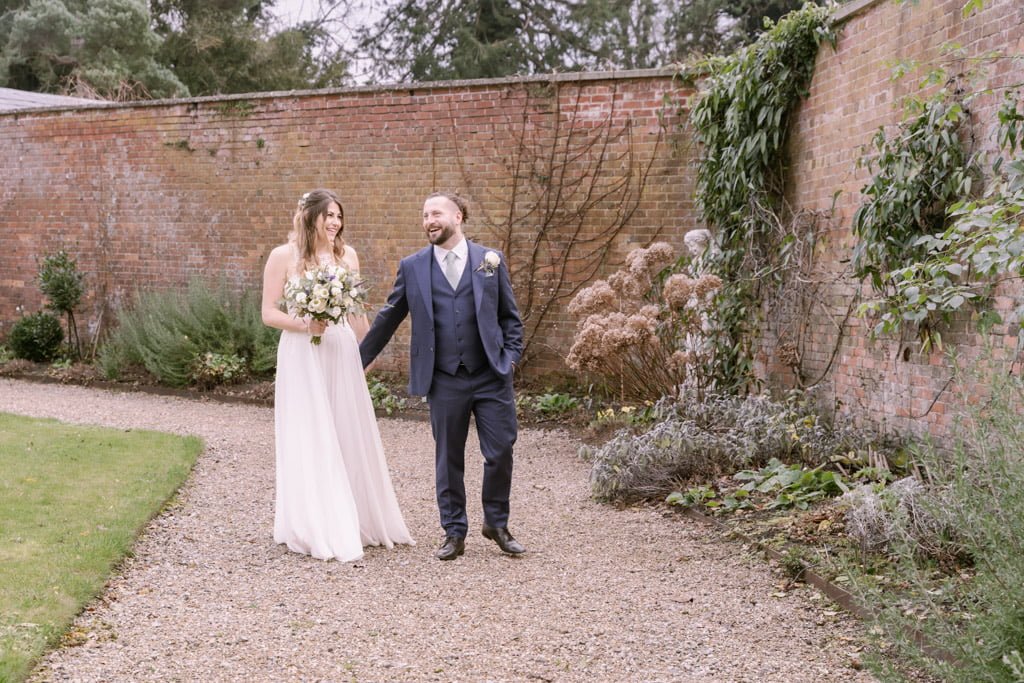 a bride and groom walking through a garden.