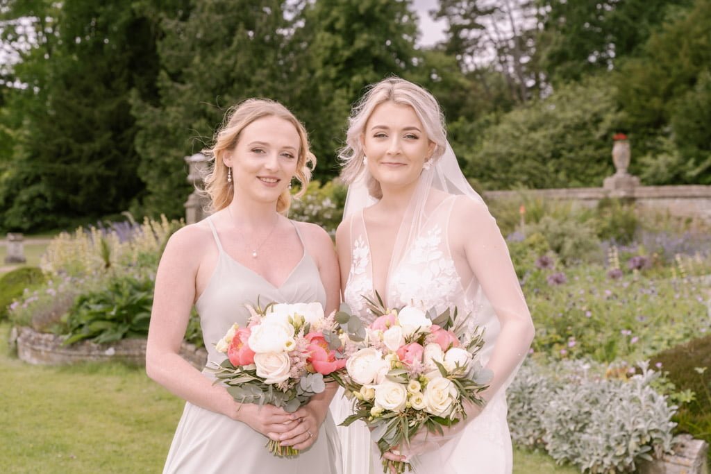 two women standing next to each other holding bouquets.