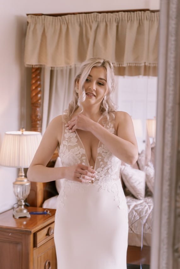 a woman in a wedding dress standing in front of a mirror.