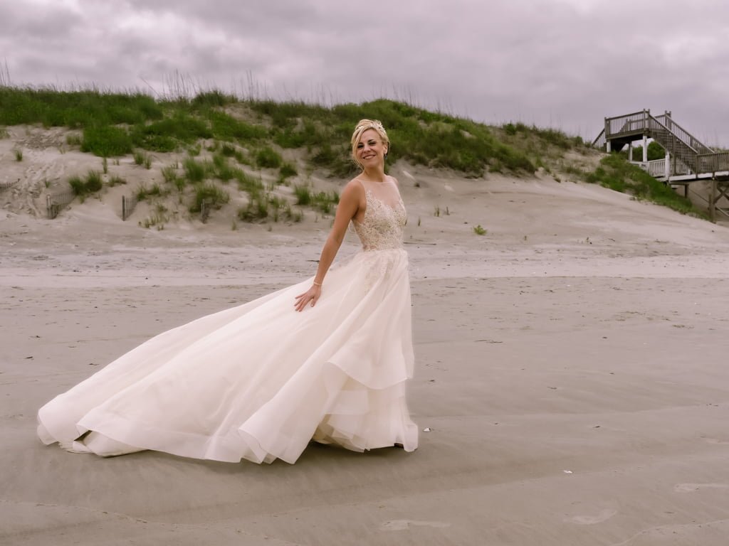 a woman in a wedding dress standing on a beach.