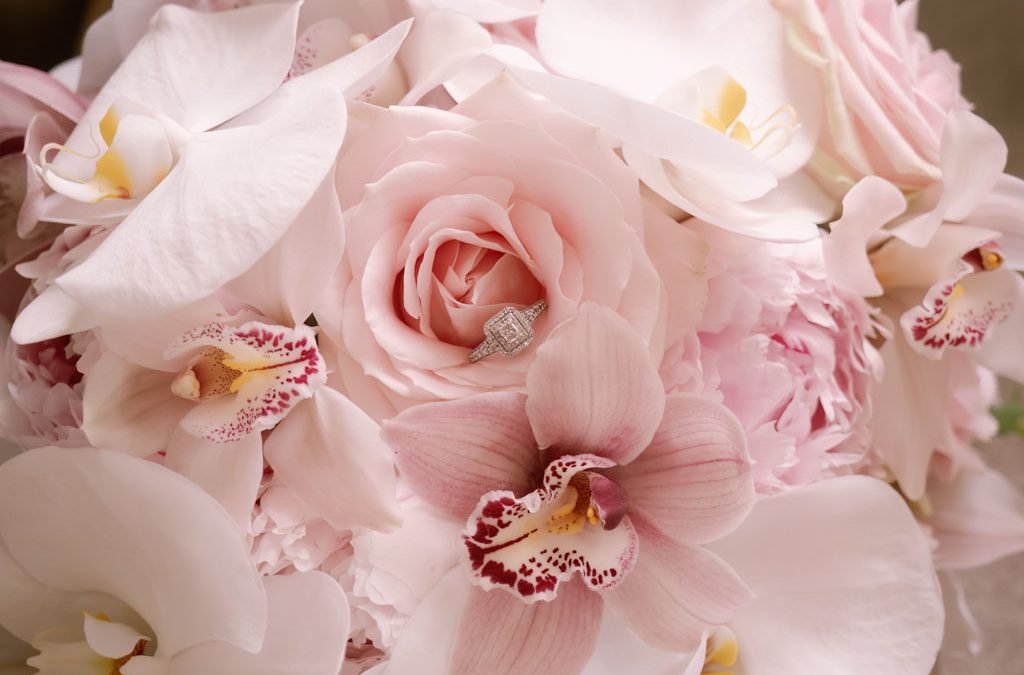 a bouquet of pink flowers with a diamond ring.
