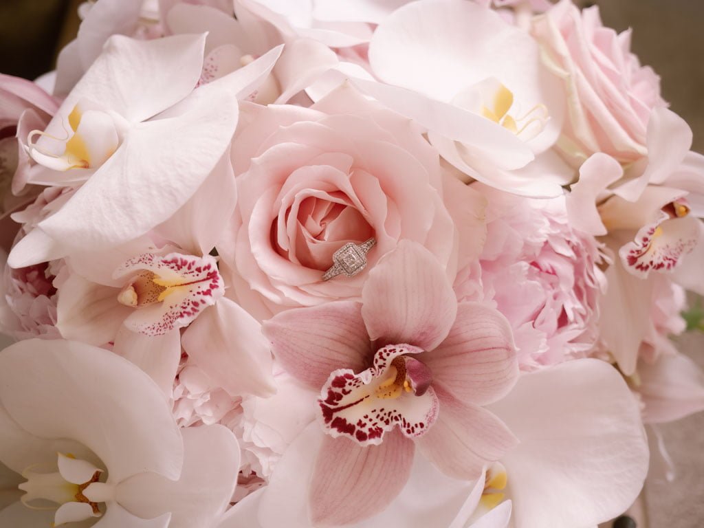 a bouquet of pink flowers with a diamond ring.