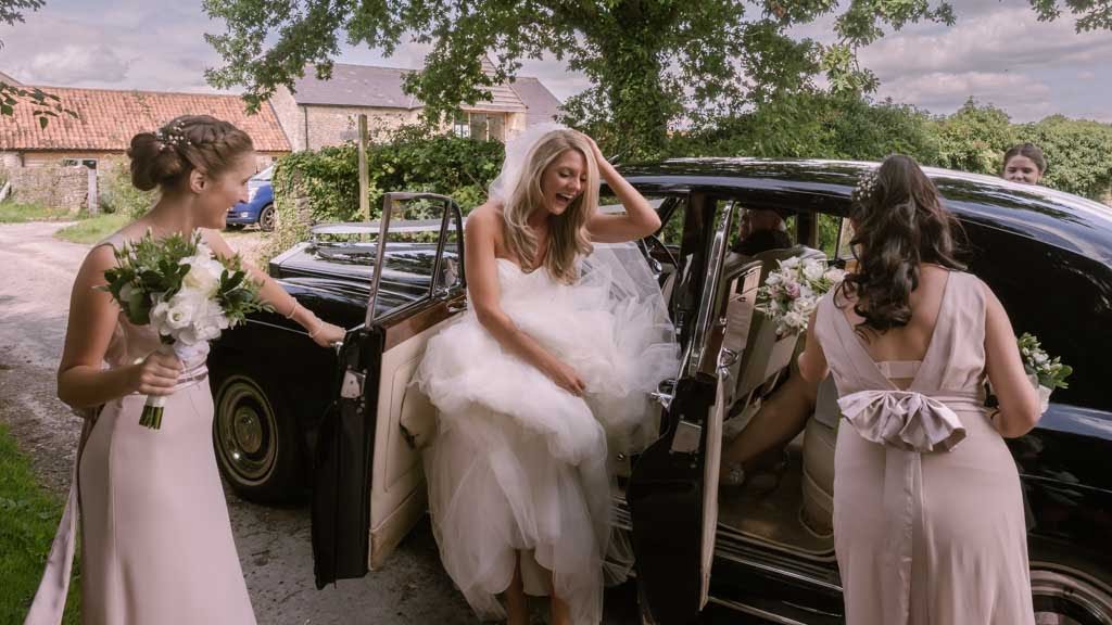 a bride getting out of a car with her bridesmaids.