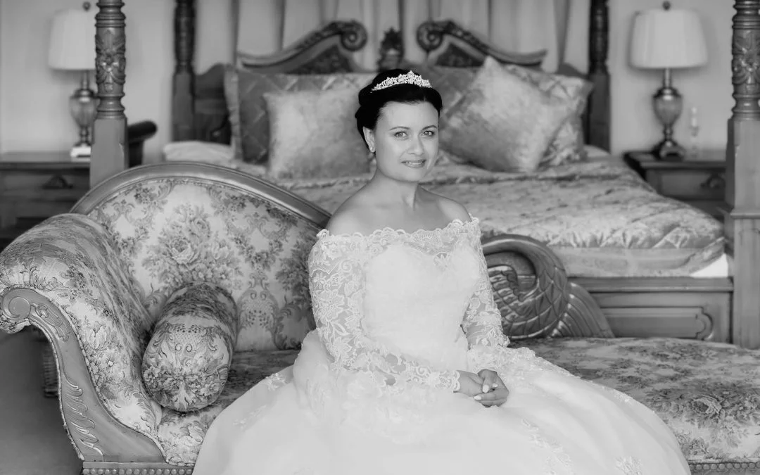 a black and white photo of a woman in a wedding dress sitting on a couch.