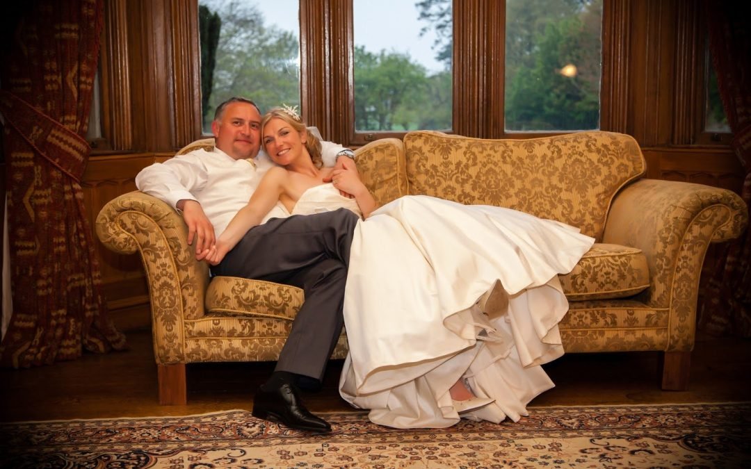 a bride and groom sitting on a couch.