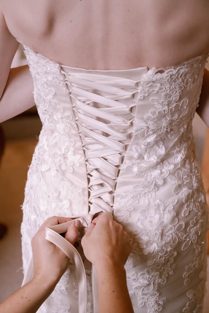 a woman in a wedding dress is tying a dress.