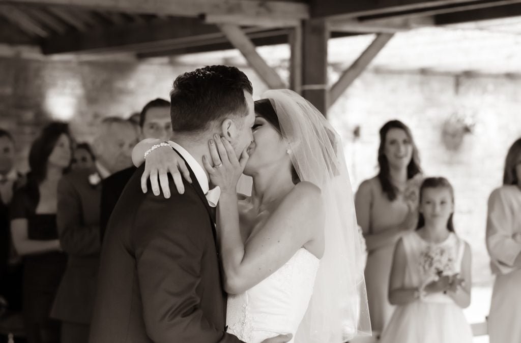 a bride and groom kissing in front of a group of people.