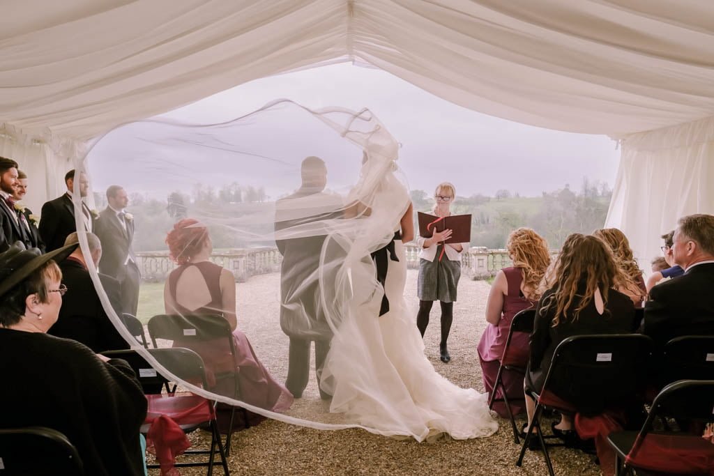 a bride and groom standing under a veil.