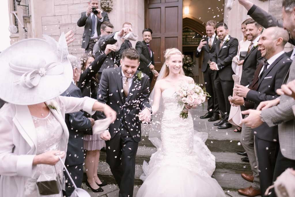 a bride and groom walk down the aisle as confetti flies in the air.