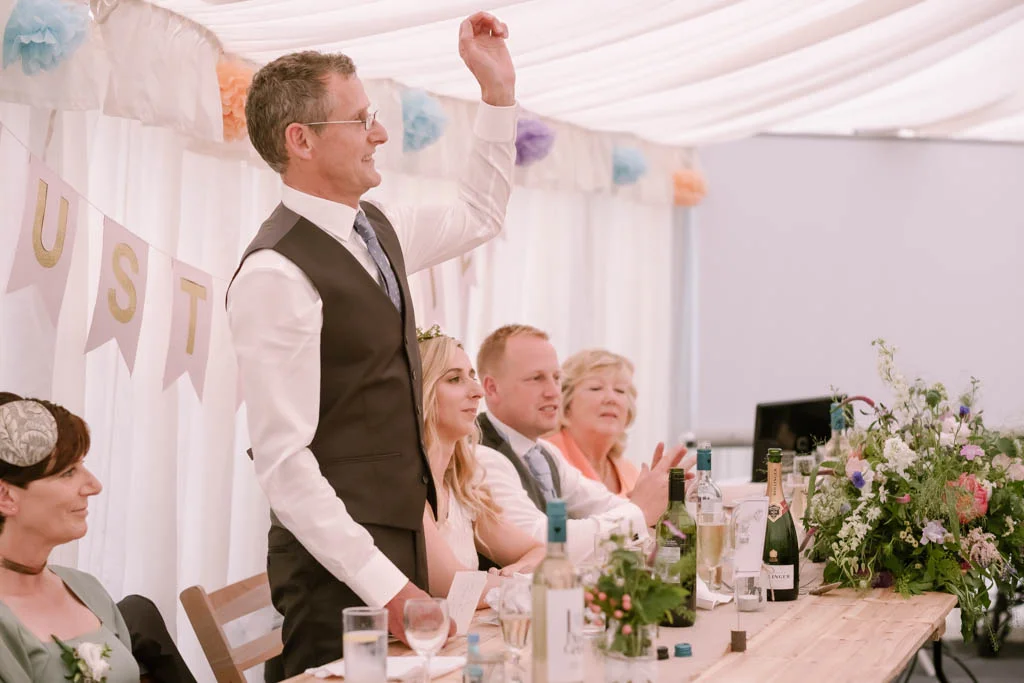 a man giving a speech at a wedding reception.