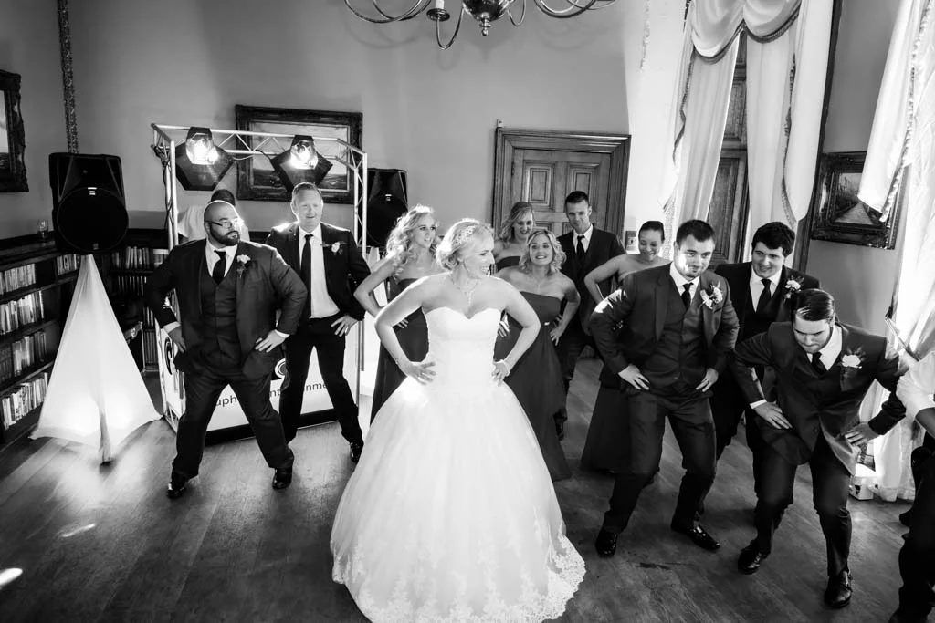 a group of people standing around a bride and groom.