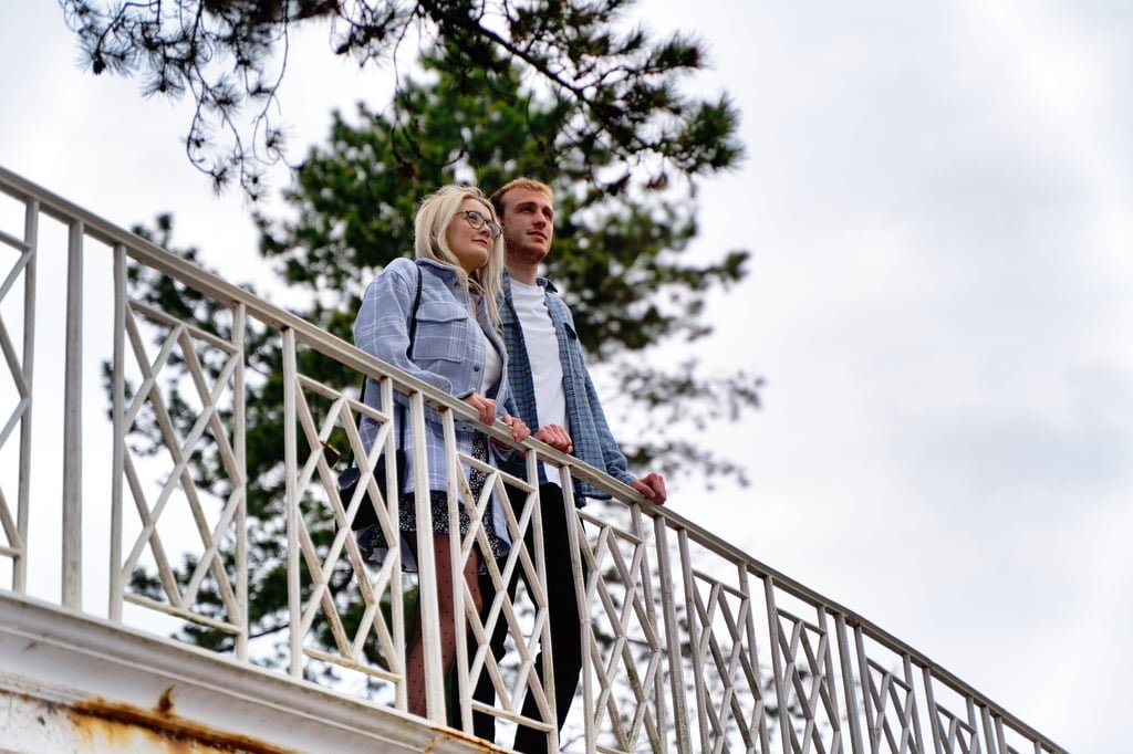 a man and a woman standing on a bridge.