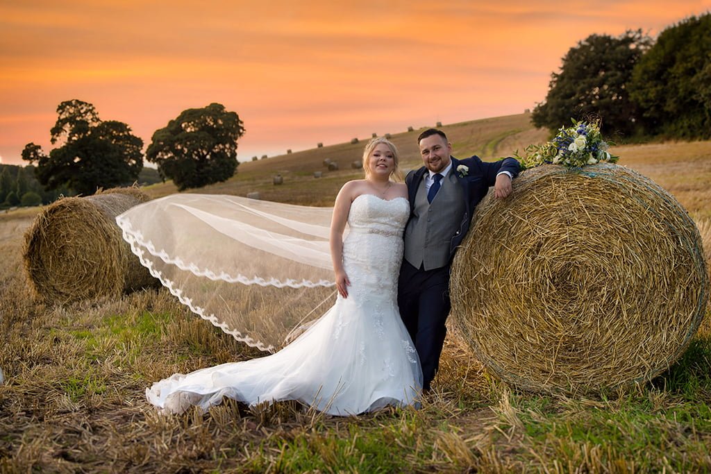 a bride and groom posing for a picture in a field.