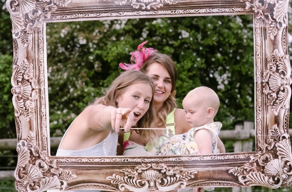 two women and a baby taking a picture in a mirror.
