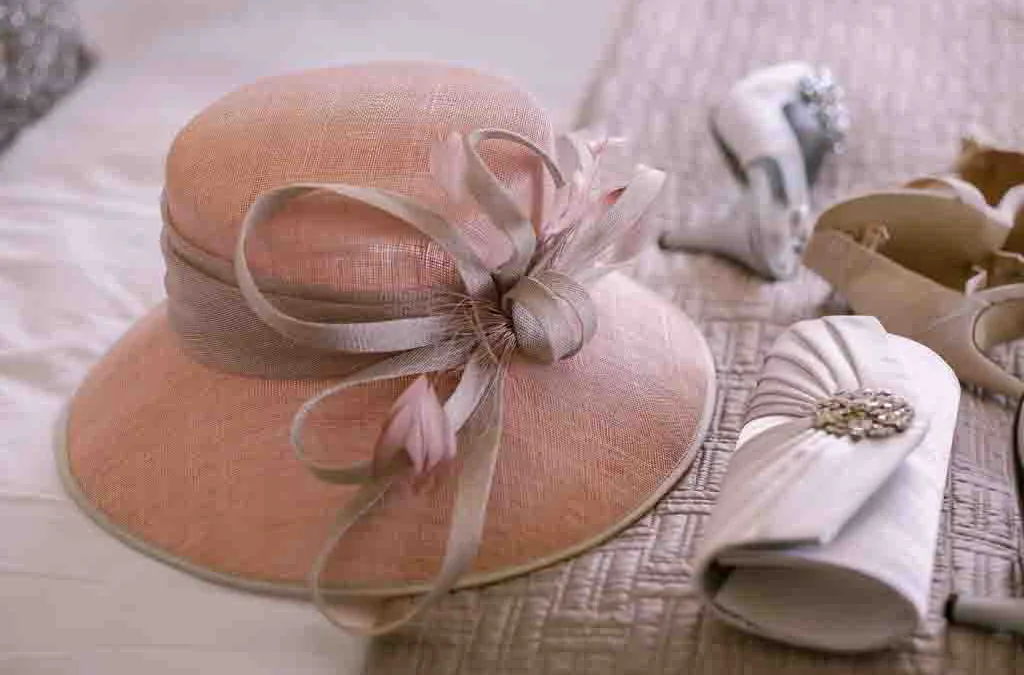 a pink hat with a bow on top of a bed.