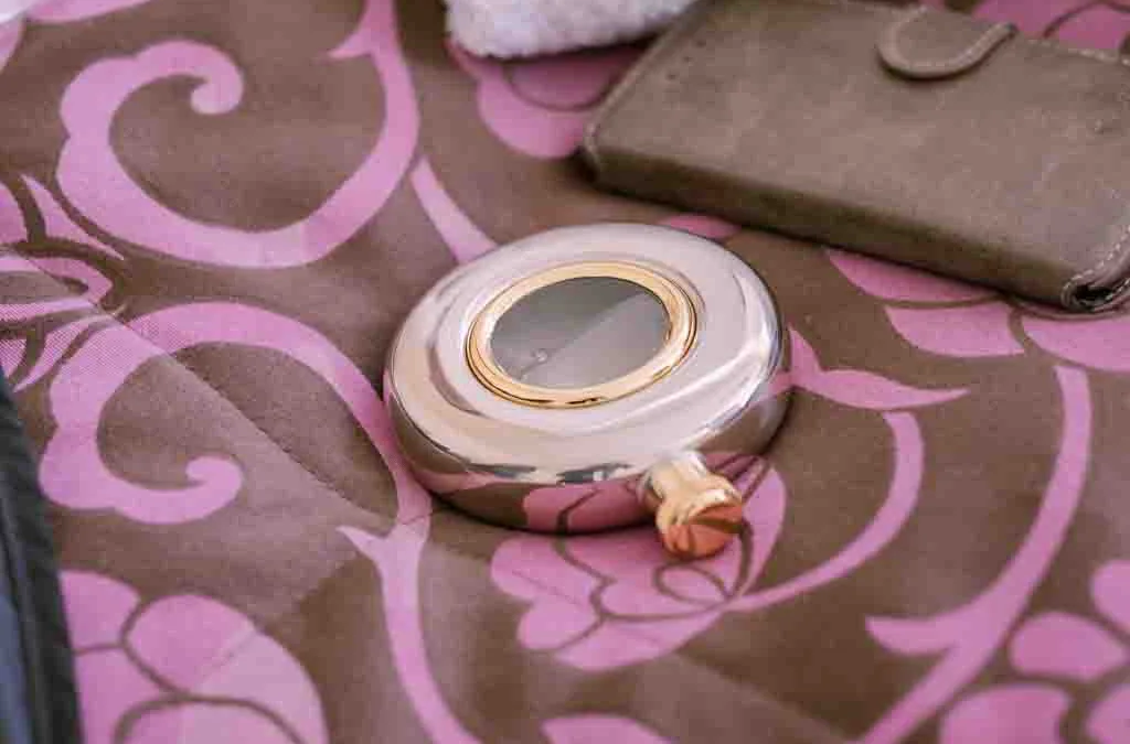 Details: a small mirror sitting on top of a pink and brown blanket.