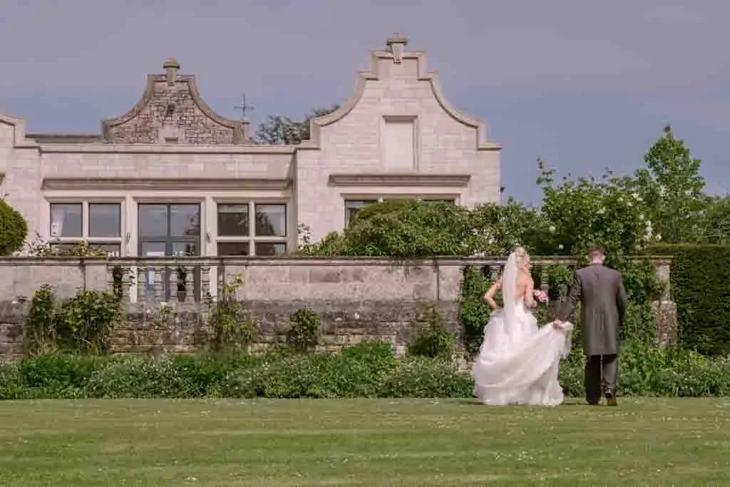 a bride and groom walking in front of a Old Down house Wedding Venue