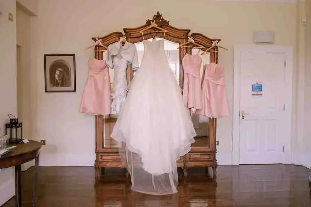 a bride's wedding dress hanging in front of a mirror.