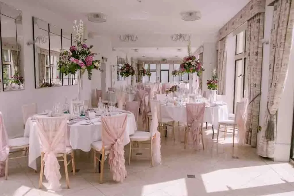a room filled with tables and chairs covered in pink cloths.