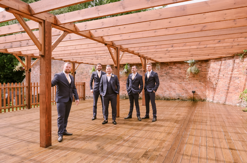 a group of men in suits standing under a wooden structure.