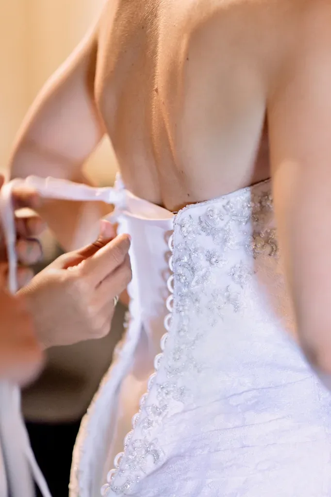 a bride is putting on her wedding dress.