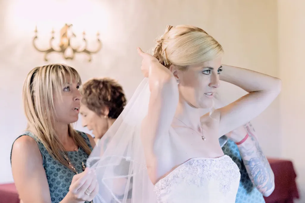 a woman in a wedding dress is putting on a veil.