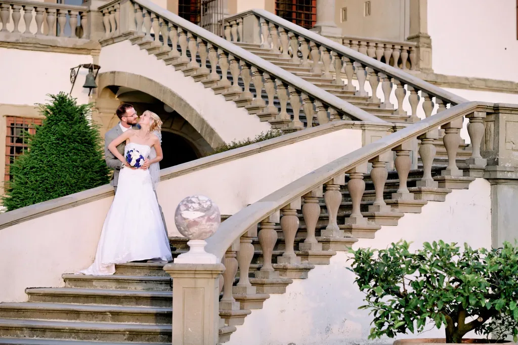 a bride and groom standing on the steps of a mansion.