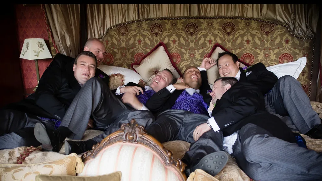Wedding Photographer Orchardleigh House: a group of men laying on top of a bed.