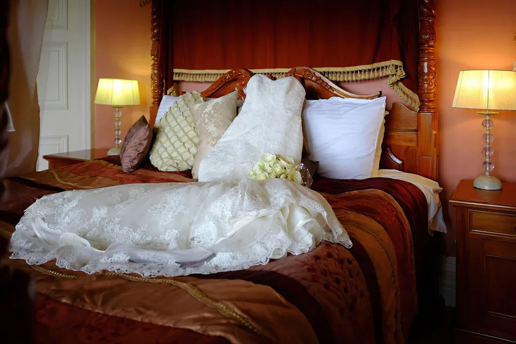 Orchardleigh Weddings:a bridal gown on a bed in a hotel room.