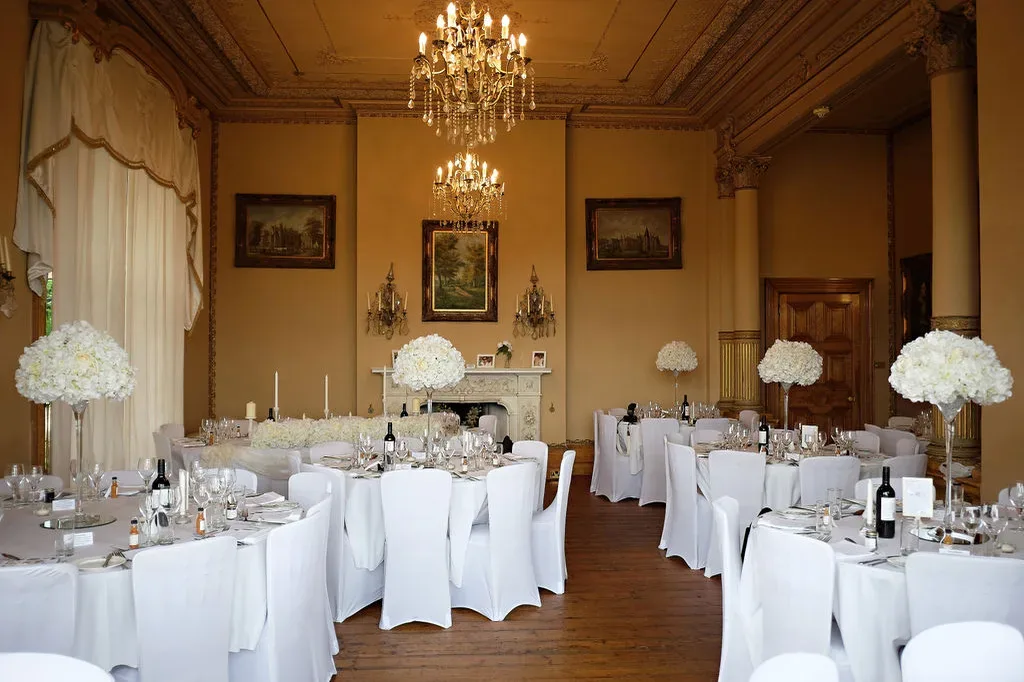 a room with tables and chairs covered in white linens.